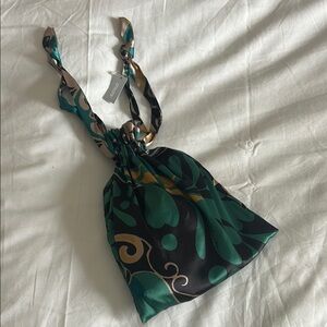 Chico's Green and Black pouch filled with a silky pillow case and sleep mask